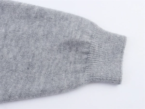 Detailaufnahme von grauem Strickpullover mit elastischen Rippbündchen und weicher Textur