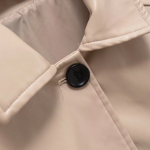 Beige faux leather jacket detail featuring a black button and fine stitching texture