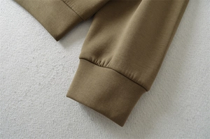 Détail des poignets côtelés et de l'ourlet sur un sweat à capuche kaki en maille dense