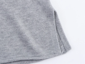 Detail eines grauen Strickpullovers mit Seitenschlitz und feinem Saumdesign