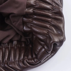 Détail de la manche d'une veste en similicuir marron avec poignets élastiques et coutures
