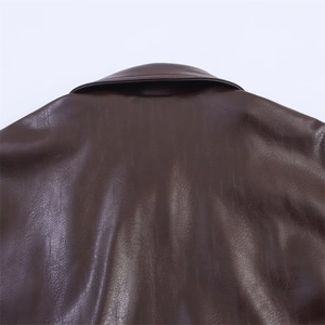 Détail macro du col d'une veste en simili cuir marron foncé avec texture fine et coutures nettes