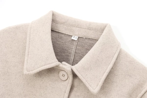 Detail of oatmeal beige wool coat collar with XS size tag and matching button