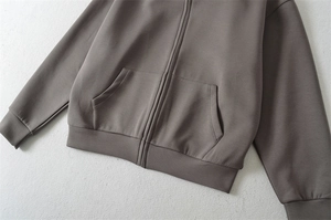 Détail du sweat à capuche zippé taupe avec poignets côtelés et texture de tissu premium