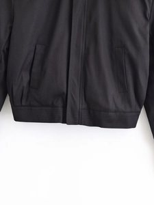 Detail view of black jacket showing ribbed hem stitching and functional side pocket