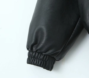 Détail des poignets élastiques sur une veste en similicuir noir avec texture litchi