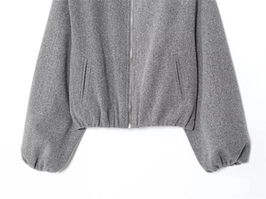 Detail of grey pilot jacket featuring metallic zipper and ribbed elastic hemline texture