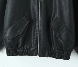 Détail d'un blouson aviateur noir en cuir avec poches latérales et ourlet élastique