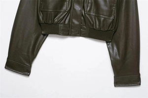 Detail of olive green faux leather jacket featuring elastic hem and large cargo pockets