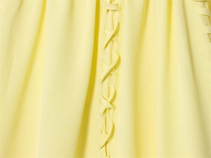 Detailansicht der hellgelben Bluse mit elegantem Schnürdetail und feiner Stoffstruktur