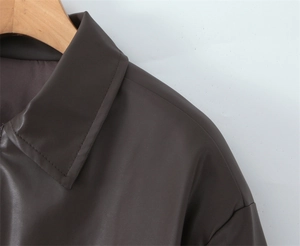 Detail of dark brown faux leather jacket collar and shoulder stitching on wooden hanger