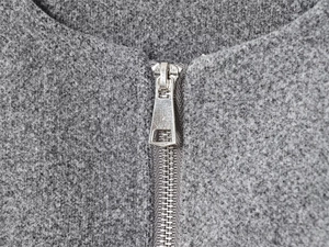 Detailed macro view of the silver metal zipper and textured grey bomber jacket fabric