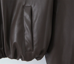 Macro shot of brown PU leather jacket featuring side pocket and elastic hem detail