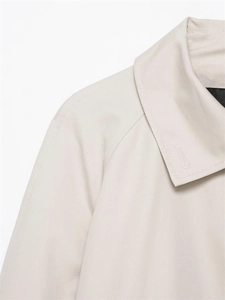 Detailed close-up of light beige waterproof trench coat collar and raglan sleeve seams