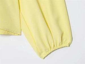 Detail von hellgelben Laternenärmeln mit elastischen Faltenbündchen an einer Chiffonbluse