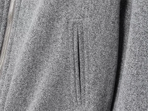 Macro shot of dark grey wool blend fabric texture with detailed metal zipper and hidden pocket