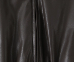Macro detail of brown faux leather texture and metallic zipper on retro winter jacket