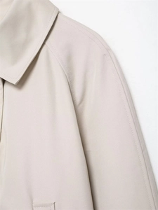 Detailed view of beige trench coat lapel and shoulder stitching with fine twill texture