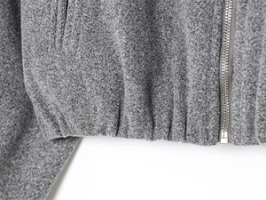 Close-up of thick gray jacket fabric with elastic hem and metallic silver zipper detail