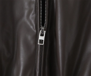 Detailed close-up of a silver zipper on a brown leather jacket with smooth texture