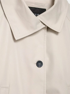 Close-up of beige trench coat featuring lapel collar, fine stitching and matte button