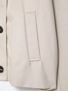 Detail shot of khaki trench coat pocket with black buttons and twill fabric texture