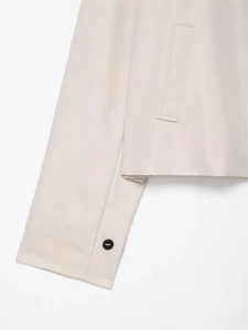 Detail of light beige twill jacket showing side pocket and single black button cuff