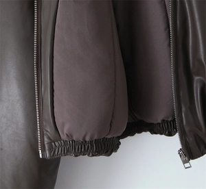 Detail view of the high-quality brown faux leather jacket texture and silver metal zipper
