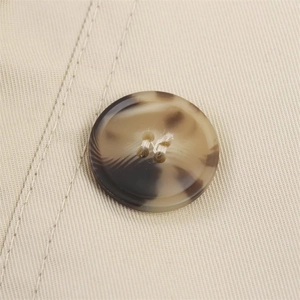 Macro shot of a tortoise shell resin button on khaki twill fabric with double stitching