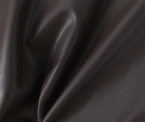 Macro detail of dark brown faux leather material with fine lychee texture and soft folds