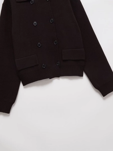 Détail d'un cardigan en tricot marron foncé à double boutonnage avec poches à rabat