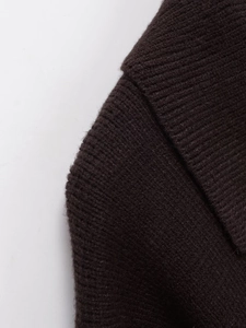 Détail du tricot épais marron foncé montrant le col à revers et la texture de l'épaule