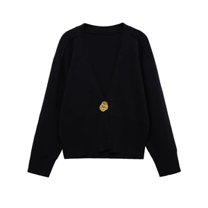 Detail of V-neck black knit cardigan featuring a unique irregular gold metal button
