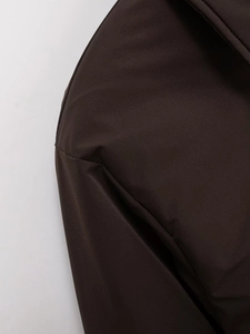 Close-up of premium dark brown faux suede fabric texture and stitching on the jacket