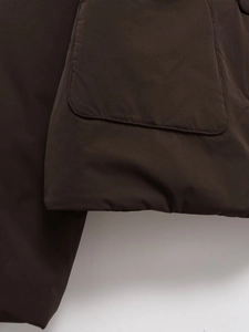 Close-up of the square pocket flap and stitched hem on a brown faux suede jacket