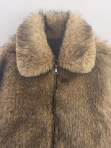 Détail d'une veste en fausse fourrure marron avec de larges revers et une fermeture éclair