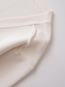 Close-up of premium white knit sweater featuring ribbed neckline and fine texture