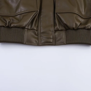 Detailed macro view of olive green PU leather jacket with ribbed elastic hem and flap pockets