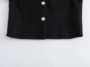Detail of tweed texture and golden metal buttons on the pocket of a black wool jacket