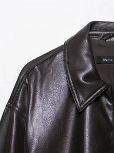 Detailed macro view of dark brown leather jacket collar and premium stitching textures