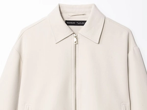 Détail de la veste zippée blanc cassé avec col classique et quincaillerie en métal argenté