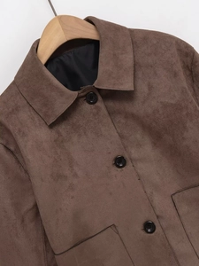 Detail view of brown suede jacket with large black buttons and textured fabric
