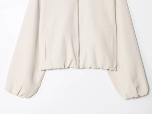 Vue détaillée d'une veste beige zippée avec fermeture en métal et poches verticales