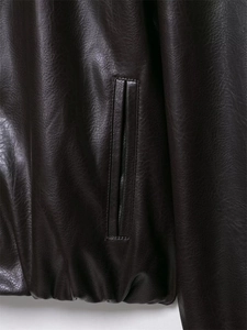 Detailed macro of the dark brown leather bomber jacket side pockets and ribbed hem texture