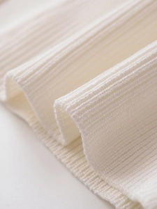 Detailed close-up of white ribbed knit fabric texture showing premium soft vertical patterns