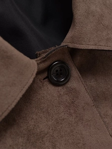 Macro detail of the brown suede jacket showing stitching and black button texture