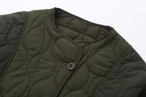 Detail shot of olive green quilted jacket featuring wave stitching and resin button closure