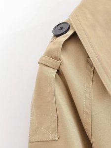Close-up of khaki trench coat epaulets with black buttons and detailed twill fabric stitching