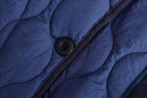 Detailed macro view of wavy quilted nylon fabric with a black button and contrast piping