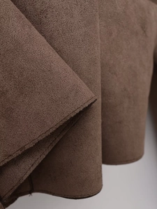 Detailed macro view of high-quality dark brown faux suede fabric texture with soft nap